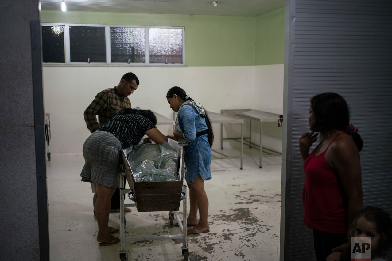 In this Feb. 4, 2017 photo, people mourn the body of a murdered family member in Manaus, Brazil. According to Claudio Lamachia, the head of Brazil's bar association, Brazil's prisons are universities of crime, and from the inside, leaders give orders to commit crimes on the outside, including assassination. (AP Photo/Felipe Dana)