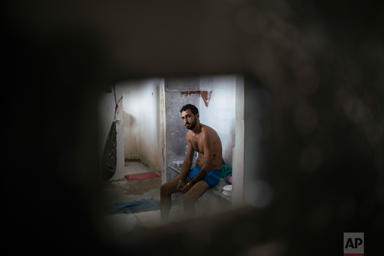 In this Feb. 2, 2017 photo, an inmate sits inside a cell separated from the main prison population, at the Monte Cristo agricultural penitentiary in Boa Vista, Brazil. Many inmates shouted that they need medical attention. (AP Photo/Felipe Dana)