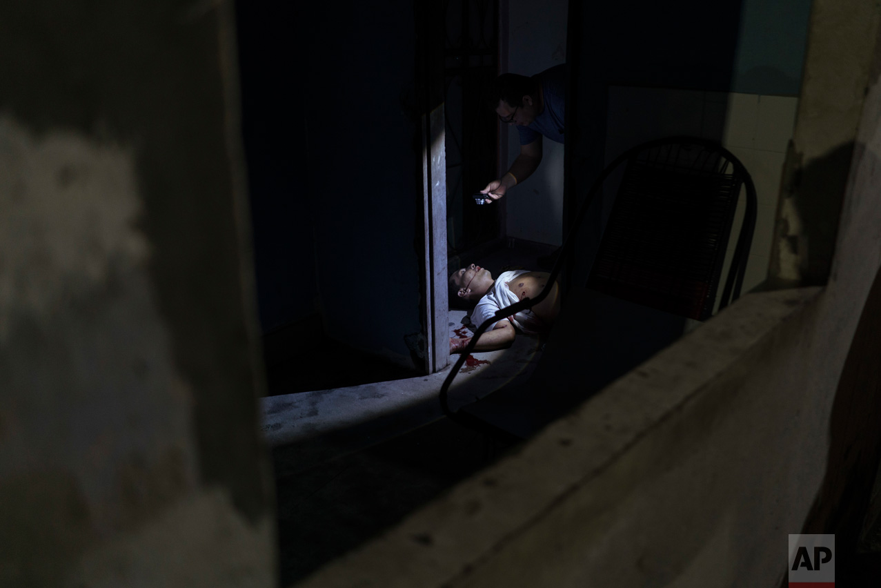 In this Feb. 5, 2017 photo, police inspect a murder victim on the floor of a home in Manaus, Brazil. The increasingly violent city is a thoroughfare for drug trafficking across South America, where authorities suspect most murders are gang related. (AP Photo/Felipe Dana)