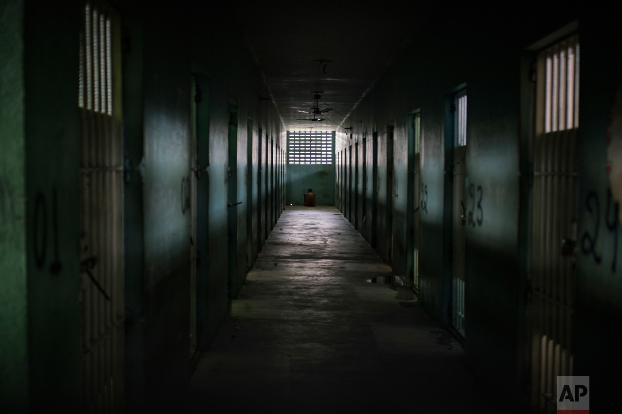 In this Feb. 2, 2017 photo, an inmate sits facing the wall at the end of a corridor between cells at the Monte Cristo agricultural penitentiary in Boa Vista, Brazil. Some prisoners serving time for lesser crimes were forced to participate in gang-driven slaughters that left at least 130 inmates dead in January. (AP Photo/Felipe Dana)