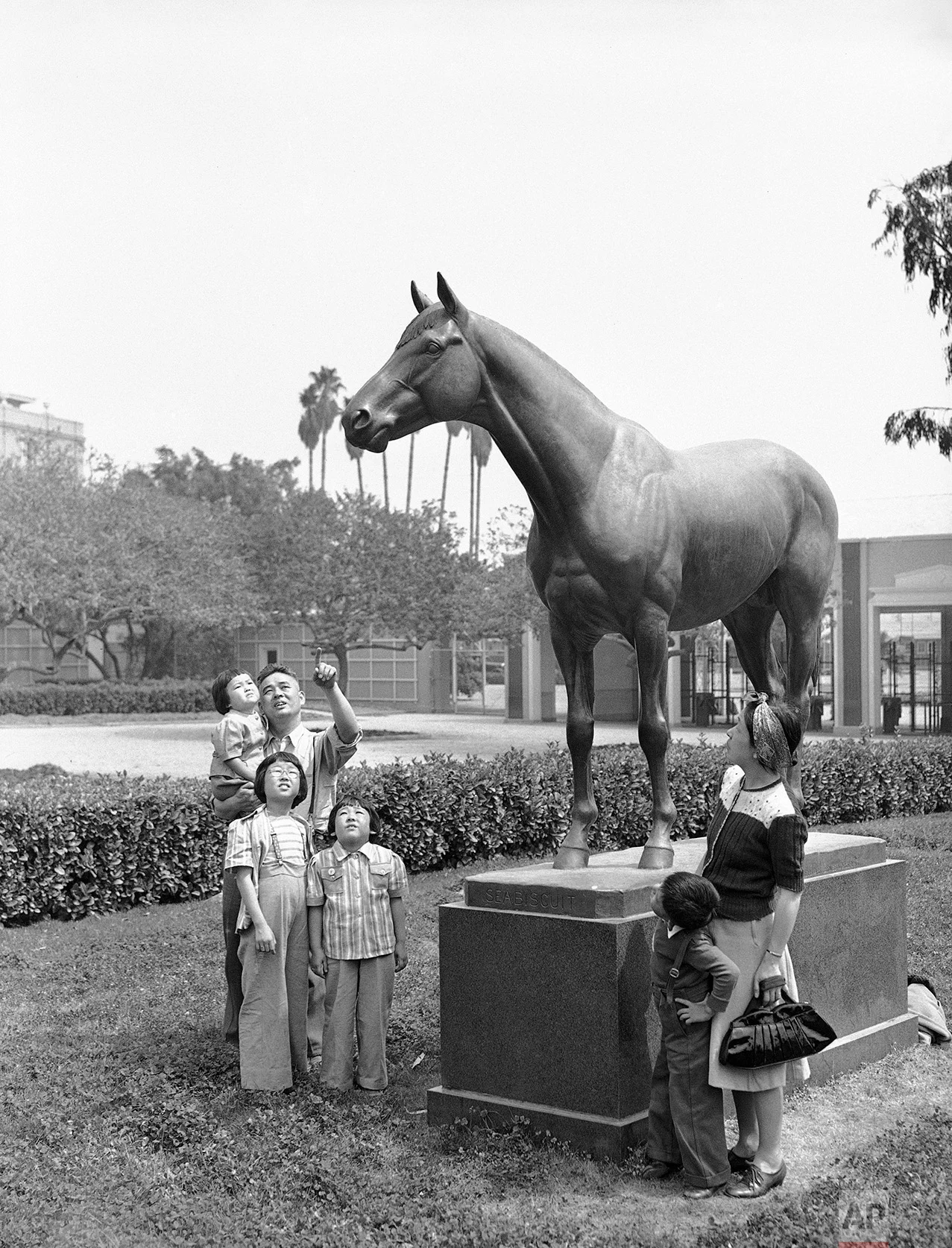 The statue of Seabiscuit, famous race horse, attracts members of an interned Japanese after they arrived at the Santa Anita race track in Arcadia, Calif., April 3, 1942. They were among the first group of evacuees to be quartered at the big racing plant which was converted into an assembly center for evacuated Japanese. (AP Photo/John T. Burns)
