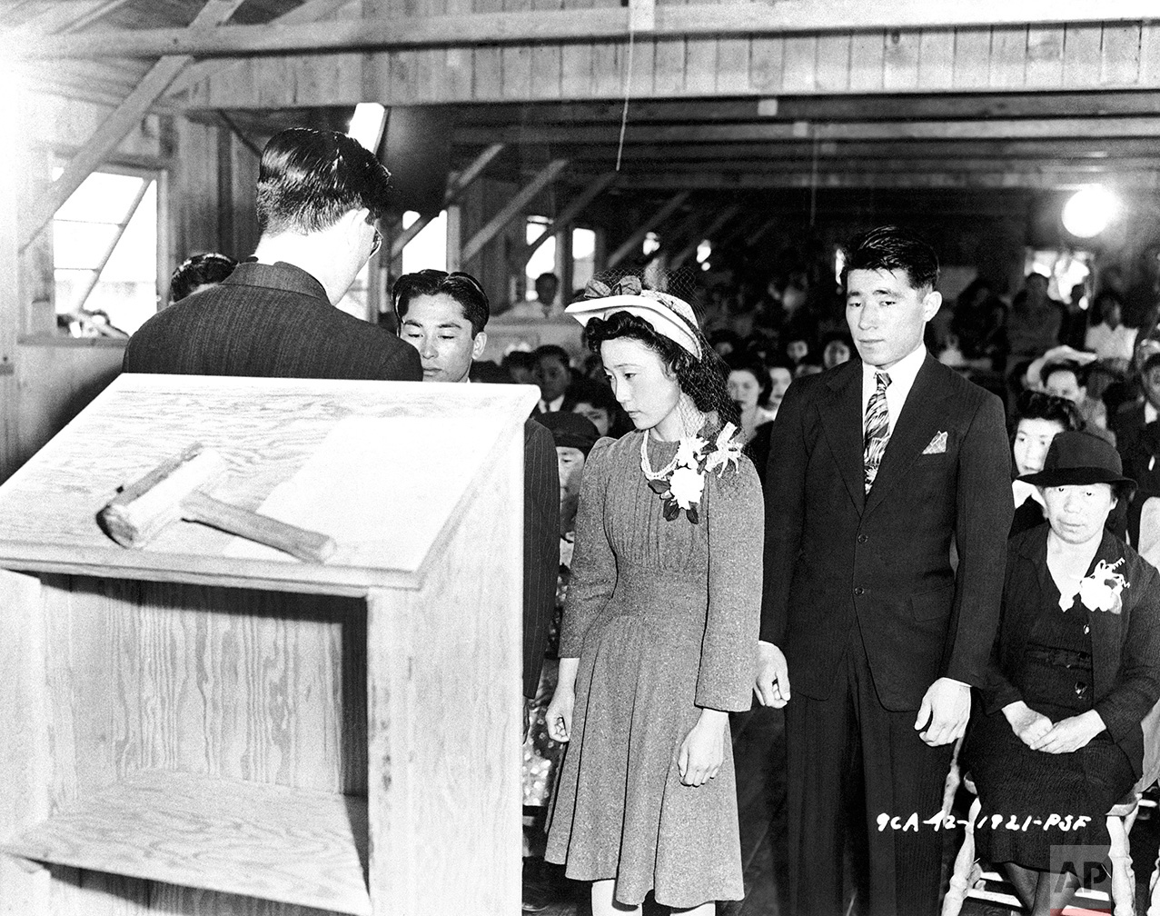 The first wedding at the assembly center. Pete Miyashito is being married to Toya Matashito, with the Reverend Donald T. Toriumi of the Presbyterian Church officiating in Santa Anita, California July 2, 1942. There are 20 Protestant Ministers and five Buddhist Priests interned at the center. (AP Photo)