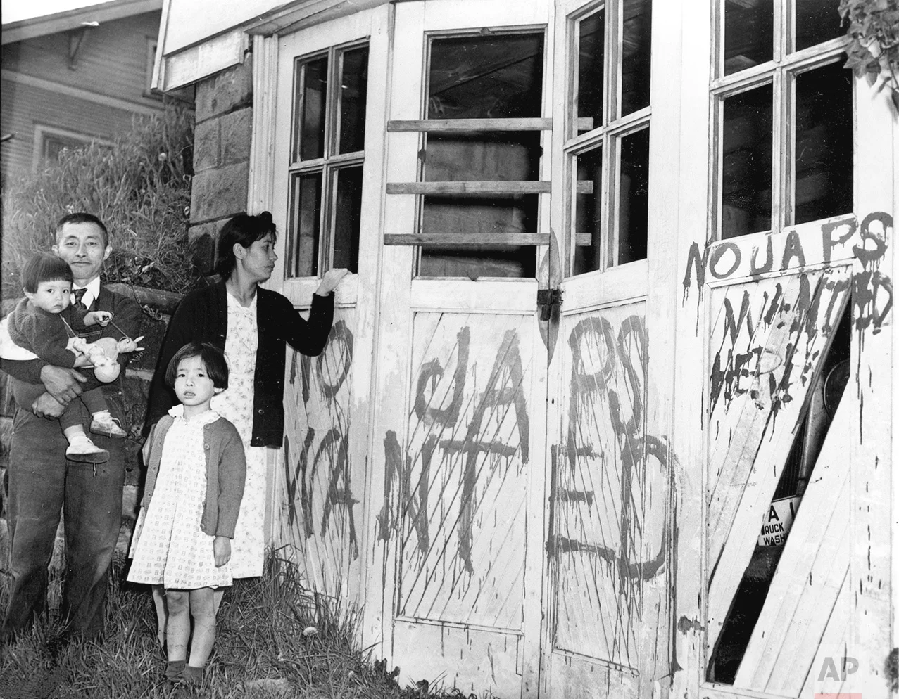 A Japanese family returns from a relocation center camp in Hunt, Idaho, to find their home and garage vandalized with anti-Japanese graffiti and broken windows in Seattle, Wa., May 10, 1945. (AP Photo)