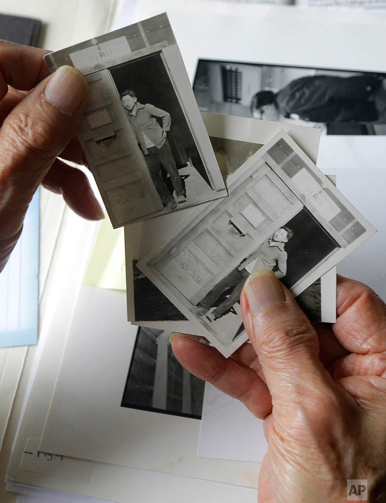 In this Feb. 10, 2017 photo, Hiroshi Kashiwagi holds 1945 photos of himself at an internment camp in Tule Lake, Calif., at his home in San Francisco. Today, Kashiwagi, 94, is a poet and writer who speaks to the public about life at Tule Lake, a maximum security camp near the Oregon border. Winters were cold, the summers hot. They were helpless against dust storms that seeped inside. "I feel obligated to speak out, although it's not a favorite subject," he said. "Who knows what can happen? The way this president is, he does not go by the rules. I'm hoping that he would be impeached." (AP Photo/Jeff Chiu)