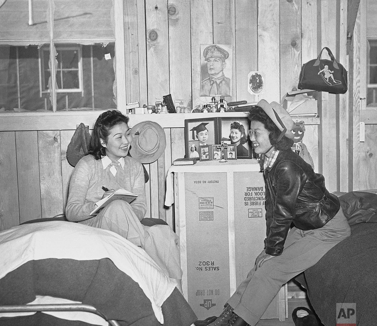 A picture of Gen. Douglas MacArthur, military nemesis of the Japanese forces, hung in a flace of honor, March 24, 1942 on the wall of the room of Gene Hashimoto (left) and Mary Wada was at the reception center established at Manzanar in the Owens Valley for Japanese evacuated from Los Angeles. Miss Hashimoto wrote friends at home of the new life at the hastily constructed community. (AP Photo)