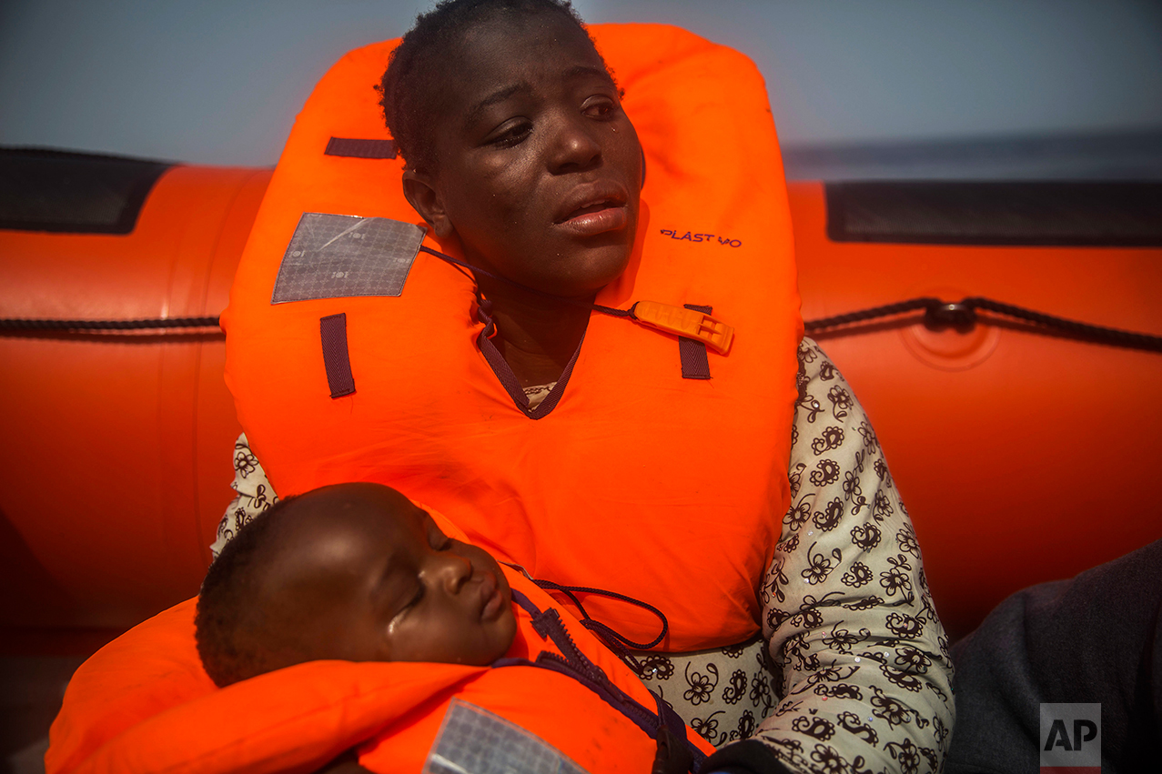 A woman from Ivory Coat holds her child, as they wait aboard a rubber boat out of control to be assisted by an NGO, 25 miles north of Sabratha, off the Libyan coast, early in the morning on Thursday, Feb. 23, 2017. (AP Photo/Santi Palacios)