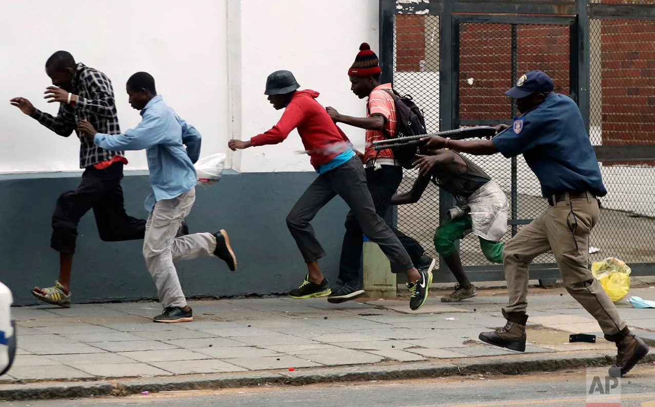 A metro police officer fires rubber bullets at anti-immigrant protesters in Pretoria, South Africa, Friday, Feb. 24, 2017. Police fired stun grenades, rubber bullets and water cannons as the latest wave of anti-immigrant protests broke out in South Africa's capital, while President Jacob Zuma condemned anti-foreigner violence and appealed for calm. (AP Photo/Themba Hadebe)