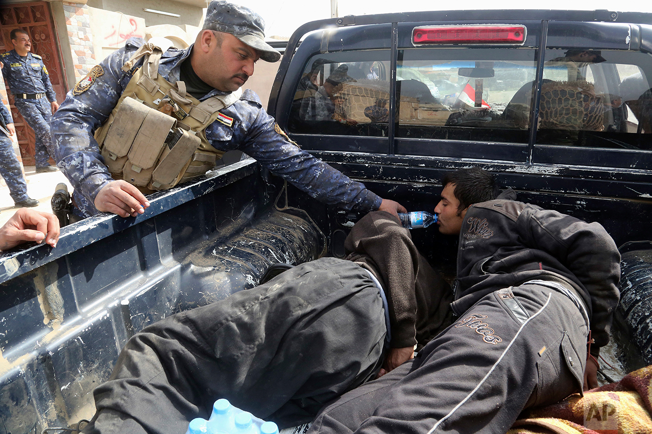  An Iraqi Federal policeman gives water to one of two handcuffed suspected Islamic State militants after they were arrested inside their home on the western side of Mosul, Iraq, Monday, Feb. 27. 2017. (AP Photo/Khalid Mohammed) 