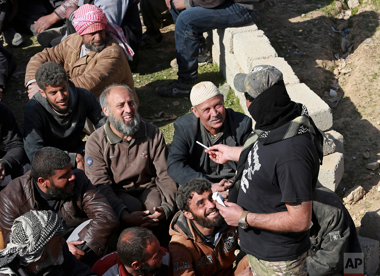  An Iraqi soldier distribute cigarettes, which were banned by Islamic State militants, to displaced men who fled their homes due to fighting between Iraqi security forces and militants as they wait for a security check at an Iraqi Army base, west of 