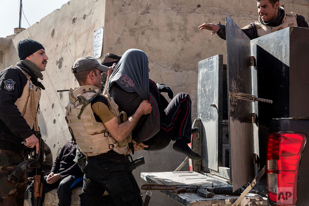  Iraqi security officers place a suspected Islamic State group member into the back of a waiting pickup truck, in east Mosul on Feb. 21, 2017. (AP Photo/John Beck) 