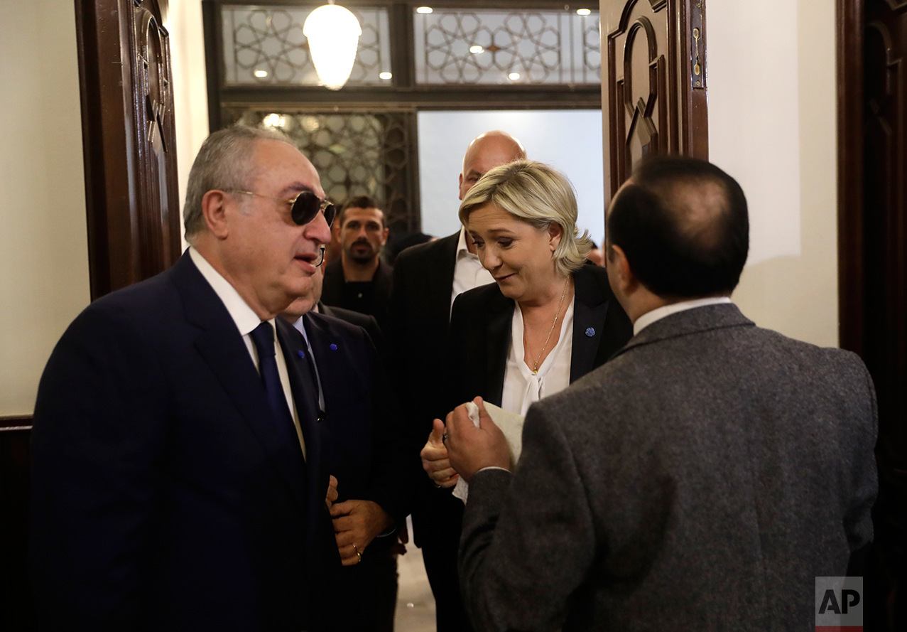  An aide of Lebanon's Grand Mufti Sheikh Abdel-Latif Derian, right, holds a head scarf as he tries to convince French far-right presidential candidate Marine Le Pen, center, to wear it during her meeting with the Mufti but she refused, at Dar al-Fatw