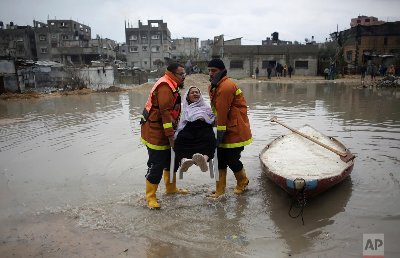  Palestinian rescue members evacuate a woman from her flooded home during a heavy rain storm in Jabaliya refugee camp, northern Gaza Strip, Thursday, Feb. 16, 2017 (AP Photo/ Khalil Hamra) 