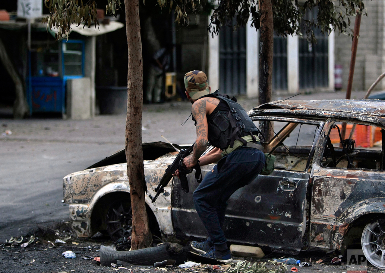  A Palestinian gunman from the Fatah movement, holds his weapon as he stands next to a charred car during clashes between the Palestinian Fatah Movement and Islamic groups in the Ein el-Hilweh refugee camp, in the southern port city of Sidon, Lebanon