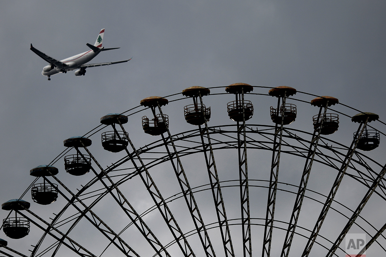  A Middle East Airlines passenger plane passes an empty Ferris wheel under cloudy skies, in Beirut, Lebanon, Sunday, Feb. 12, 2017. (AP Photo/Hassan Ammar) 