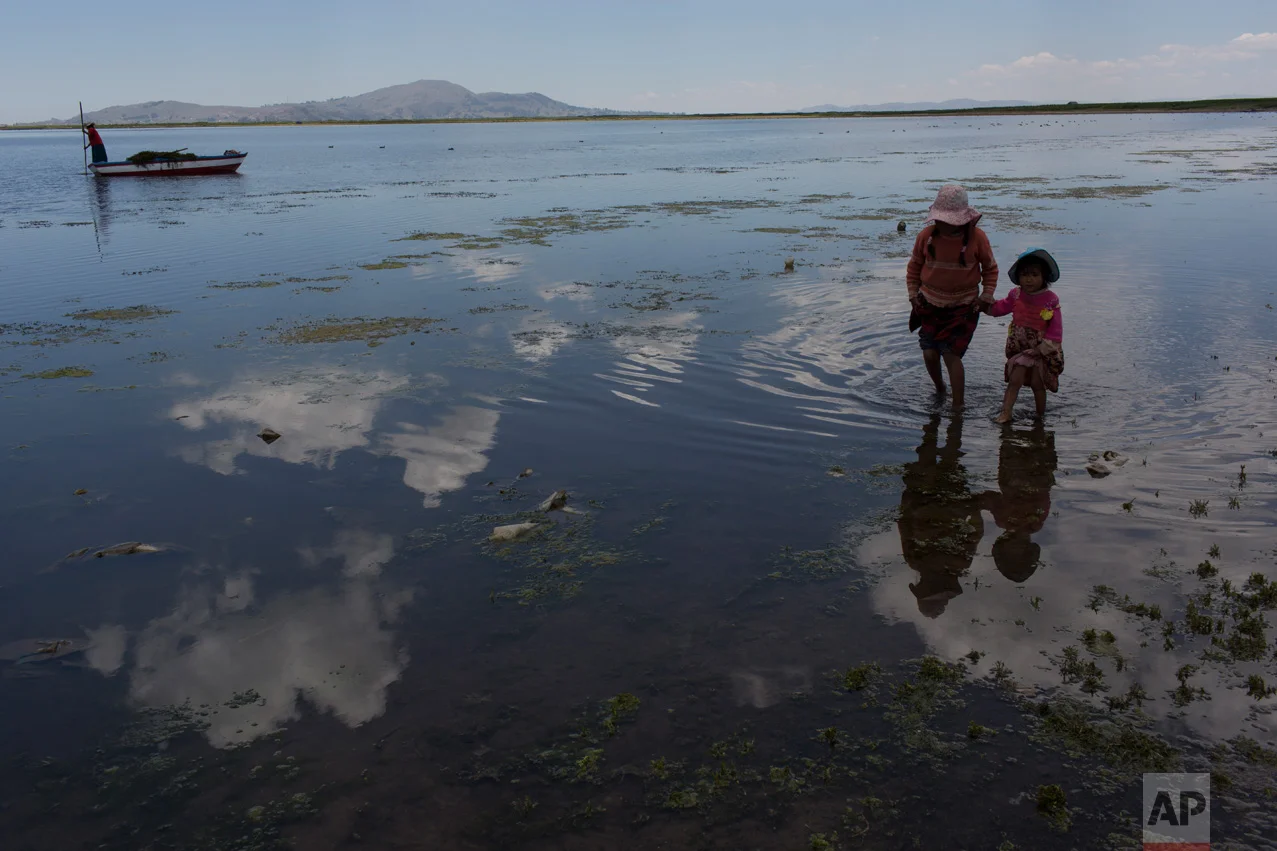 In this Feb. 2, 2017 photo, cousins from the Avila family search for discarded toys on the shores of Lake Titicaca, in Coata in the Puno region of Peru. The shores of South America's largest lake are littered with dead frogs, discarded paint buckets and bags of soggy trash. Less visible threats lurk in the water itself: highly toxic levels of lead and mercury. (AP Photo/Rodrigo Abd)