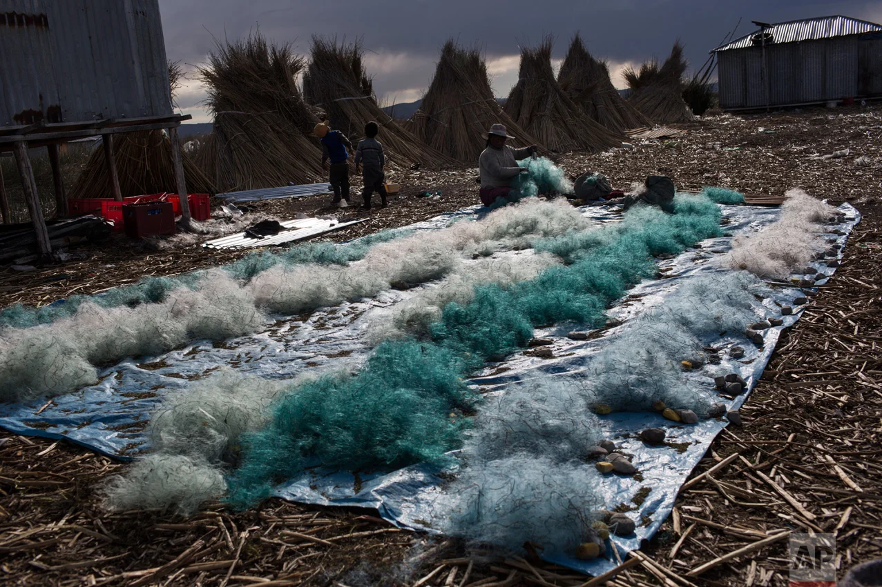 In this Feb. 4, 2017 photo, Naty Lugano Quispe cleans fish nets in Kapi Cruz Grande, a village on the shore of Lake Titicaca, in the Puno region of Peru. A 2014 study suggested officials limit some fish consumption, but area inhabitants said they weren’t informed about the study or told they could be consuming fish containing mercury, cadmium, zinc and copper at levels higher than those advised for human consumption. (AP Photo/Rodrigo Abd)