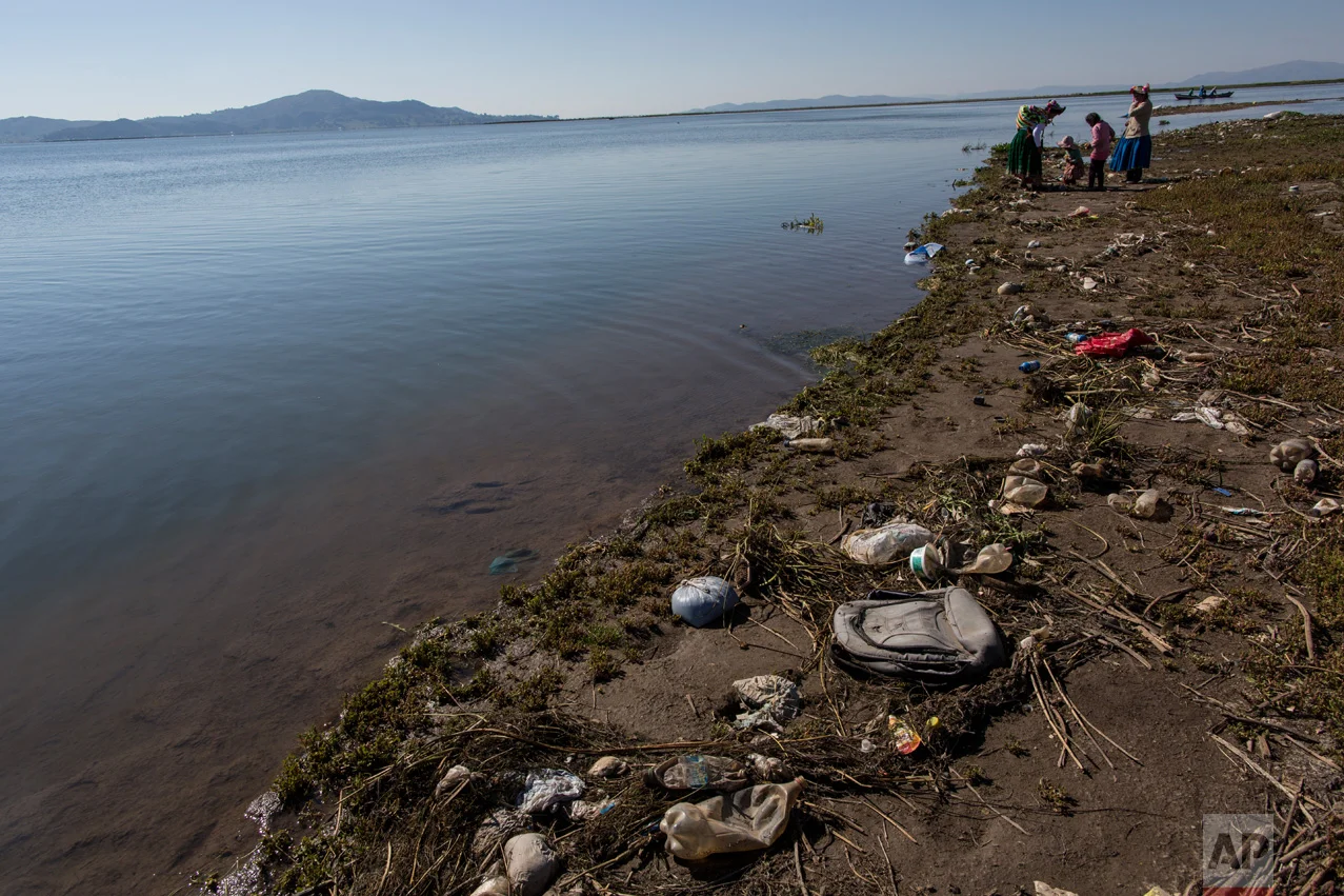 In this Feb. 3, 2017 photo, trash covers the shores of Lake Titicaca where environmental activist Maruja Inquilla talks to locals in Coata, in the Puno region of Peru. Inquillla is alerting neighboring villagers of the dangers lurking in their food and water. “If the frogs could talk they would say, ‘This is killing me,’” she said. (AP Photo/Rodrigo Abd)