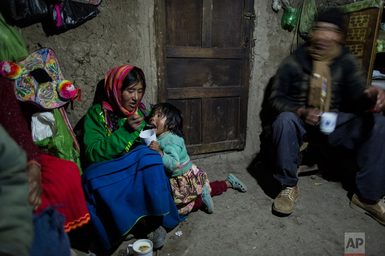 In this Feb. 4, 2017 photo, Maria Avila feeds her daughter Shomara in their family's adobe home in Coata, a village on the shored of Lake Titicaca in the Puno region of Peru. Avila grew angry as she talked about the lake’s contamination. “My ancestors have lived here more than 500 years. They have never gone through these things,” she said. (AP Photo/Rodrigo Abd)