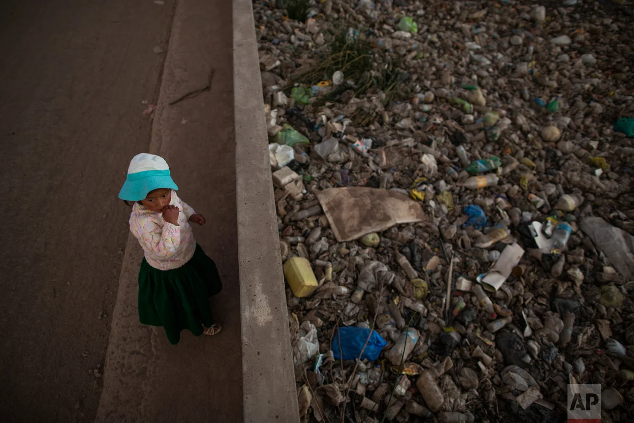 In this Feb. 1, 2017 photo, Maria Jose Campos Inquilla stands next to the trash-filled Torococha River near a municipal waste treatment plant that feeds into Lake Titicaca, in Juliaca, in the Puno region of Peru. In 2011, then-presidential candidate Ollanta Humala promised to resolve the contamination and construct water sewage processing plants. He won 79 percent of votes in the Lake Titicaca region but did not follow through. (AP Photo/Rodrigo Abd)