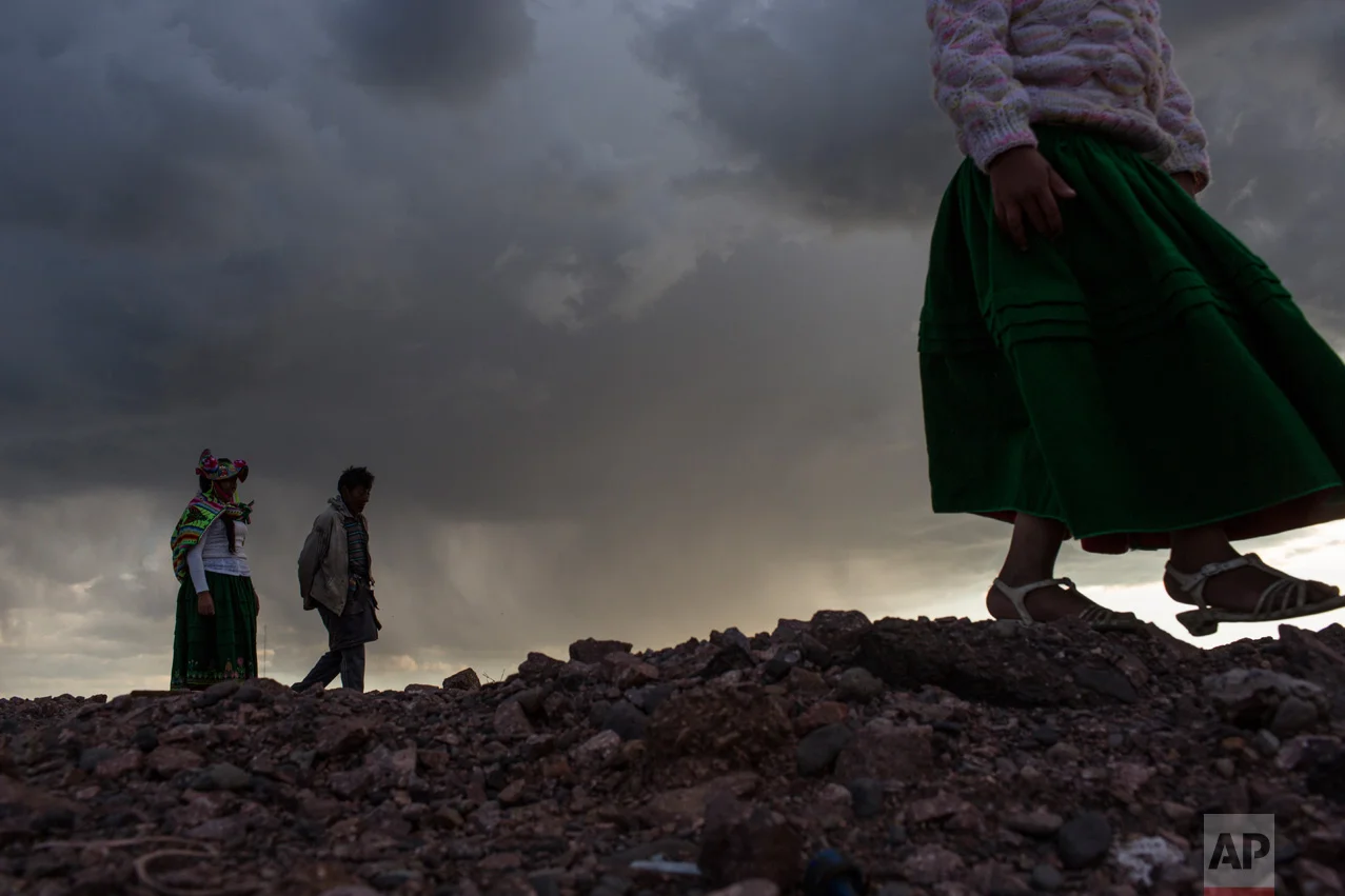 In this Feb. 1, 2017 photo, environmental activist Maruja Inquilla, left, walks with Auroro Belisario Pacompia at a municipal waste treatment plant whose waters flow into Lake Titicaca, in Juliaca, in the Puno region of Peru. Inquillla is alerting neighboring villagers of the dangers lurking in their food and water. (AP Photo/Rodrigo Abd)