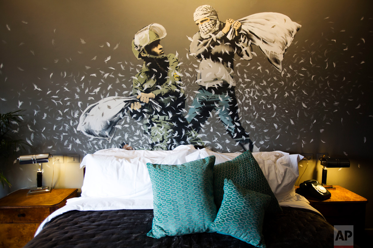  A Banksy wall painting showing Israeli border policeman and Palestinian in a pillow fight is seen in one of the rooms of the "The Walled Off Hotel" in the West Bank city of Bethlehem, Friday, March 3, 2017. The owner of a guest house packed with the