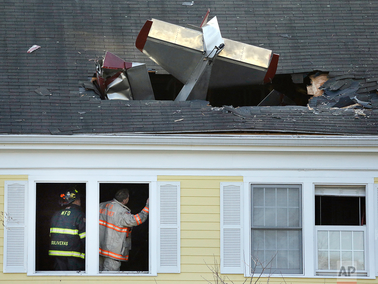  Firefighters investigate the scene after a single-engine aircraft crashed into a building across the Merrimack River from Lawrence Municipal Airport, Tuesday, Feb. 28, 2017, in Methuen, Mass. According to police, the pilot of the home-built plane wa