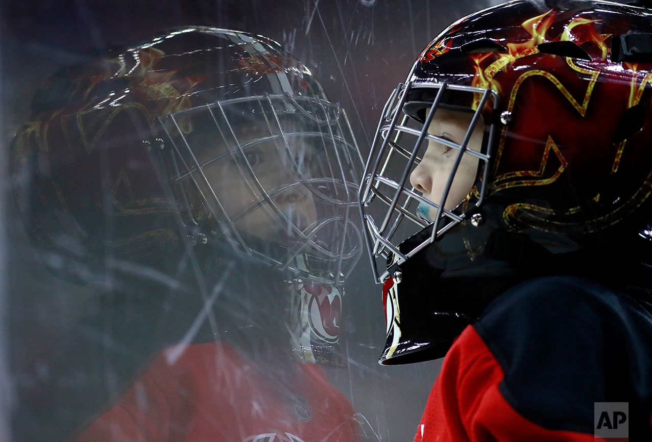  Santiago Lopes, 3, of Newark, N.J., wears a goalie helmet as he watches action during the first period of an NHL hockey game between the New Jersey Devils and the Ottawa Senators, Tuesday, Feb. 21, 2017, in Newark, N.J. (AP Photo/Julio Cortez) 