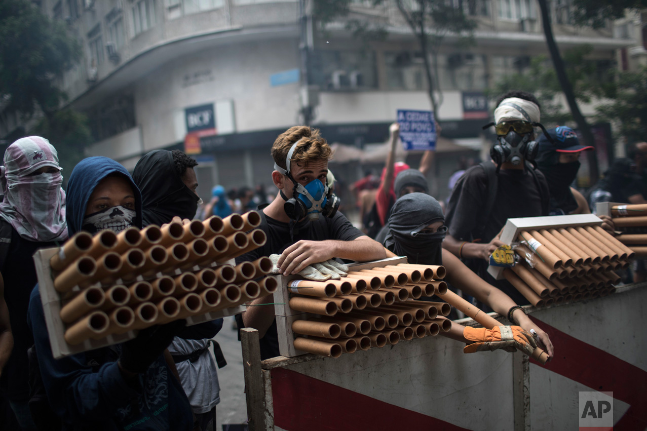  Demonstrators holding fireworks as weapons stand behind a barricade during clashes with police as they protest the state government in Rio de Janeiro, Brazil, Thursday, Feb. 9, 2017. The protesters are denouncing a proposal to privatize the state's 