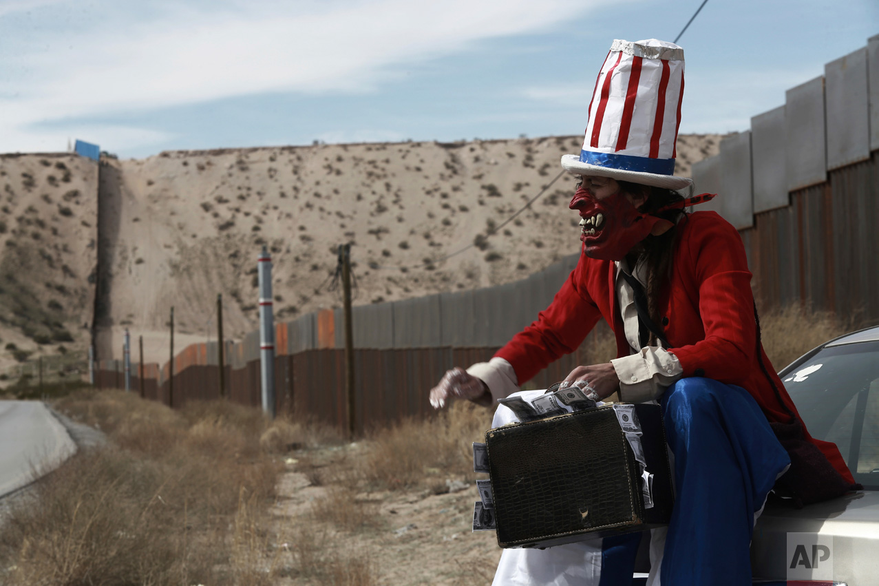  A protester dressed as a diabolical version of Uncle Sam holds a suitcase full of money at the U.S. border fence in Ciudad Juarez, Mexico, Sunday, Feb. 26, 2017. A group of about 30 protestors gathered to paint slogans on the border wall and stage a
