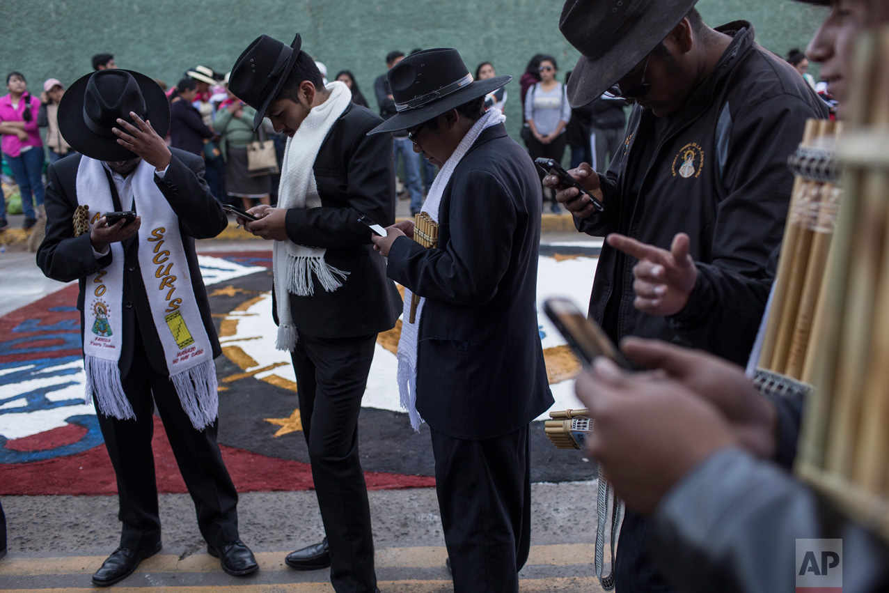 Musicians check their cell phones during a pause in the procession celebrating the feast day of the Virgin of Candelaria, in Puno, Peru, Thursday, Feb. 2, 2017. (AP Photo/Rodrigo Abd)