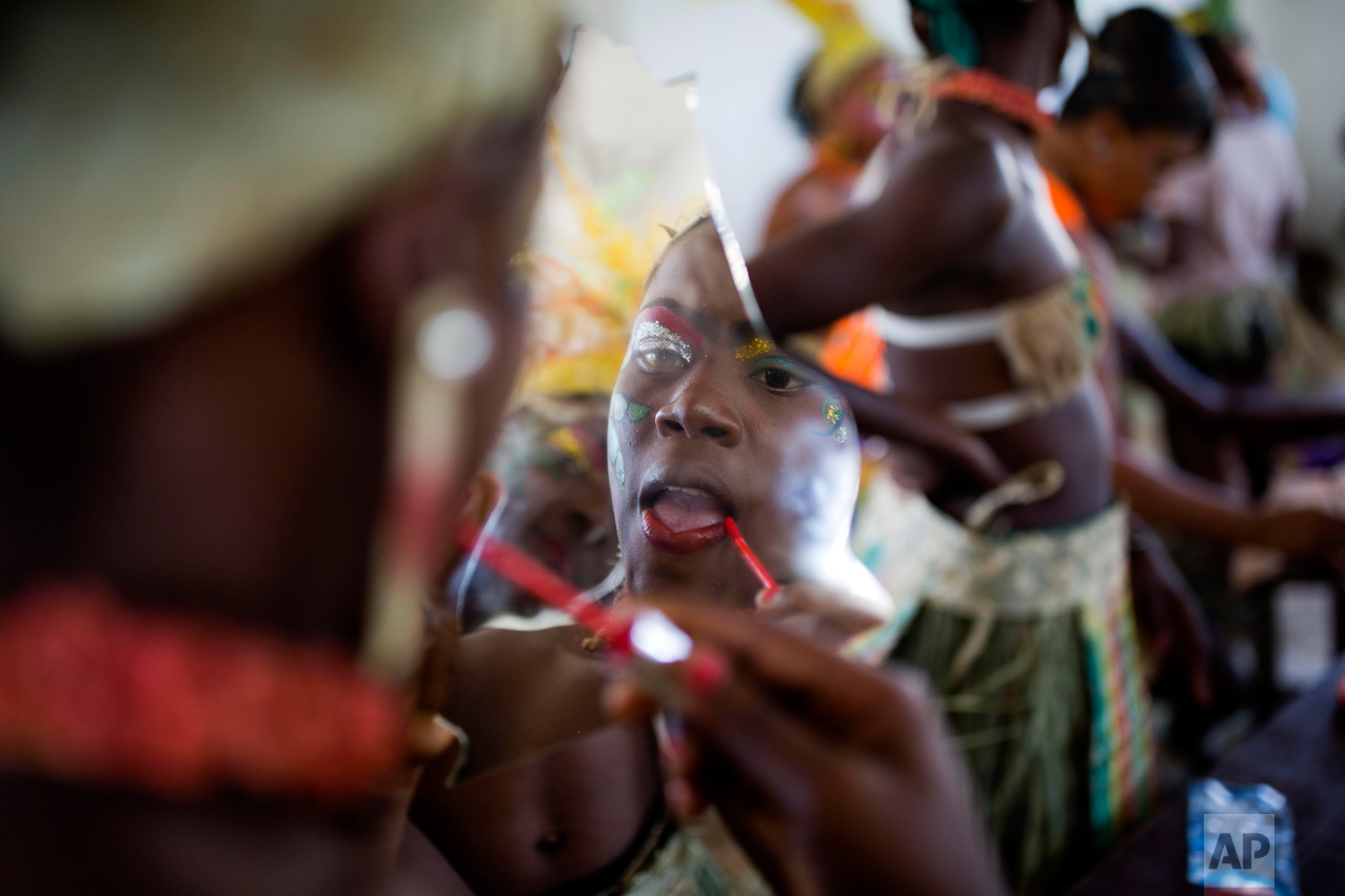 A Carnival performer holds a mirror shard as she puts on lipstick in Les Cayes, Haiti, Tuesday, Feb. 28, 2017. Haiti's three-day Carnival festivities have brought rum-fueled parties, imaginative costumes and high-energy dance music to a southern city that's still recovering from last year's punishing Hurricane Matthew. (AP Photo/Dieu Nalio Chery)