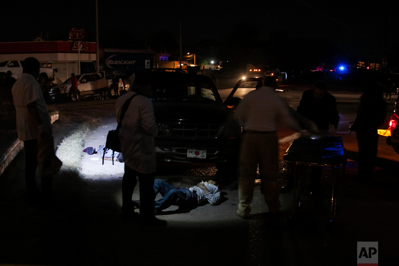 Forensic medics investigate a crime scene where two people were shot dead by unidentified attackers in Culiacan, Mexico, late Tuesday, Feb. 7, 2017. More people have been killed in Sinaloa state, hours after several suspects and a marine died during a clash in the city. (AP Photo/Rashide Frias)