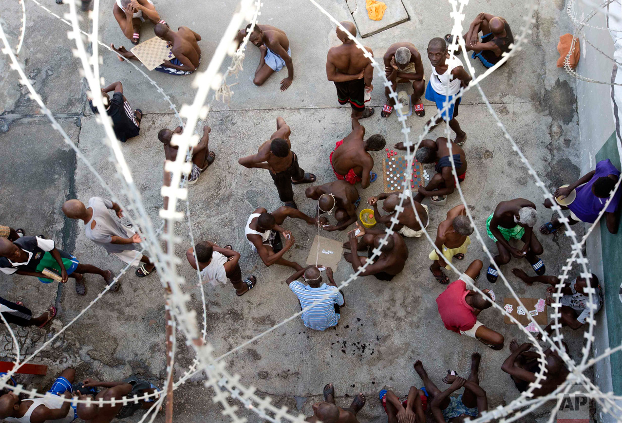 In this Feb. 13, 2017 photo, some prisoners play dominoes, checkers or card games, during recreation time inside the National Penitentiary in downtown Port-au-Prince, Haiti. Inmates, some waiting up to eight years to see a judge, try to keep their sanity by maintaining a daily routine of push-ups and lifting jugs filled with dirty water. Others play checkers or dominoes. (AP Photo/Dieu Nalio Chery)