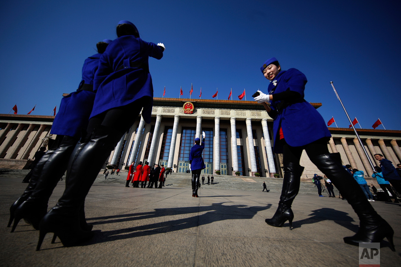 In this Sunday, March 5, 2017, photo, hospitality staff take souvenir photos in front of the Great Hall of the People where the National People's Congress is held in Beijing. (AP Photo/Andy Wong)