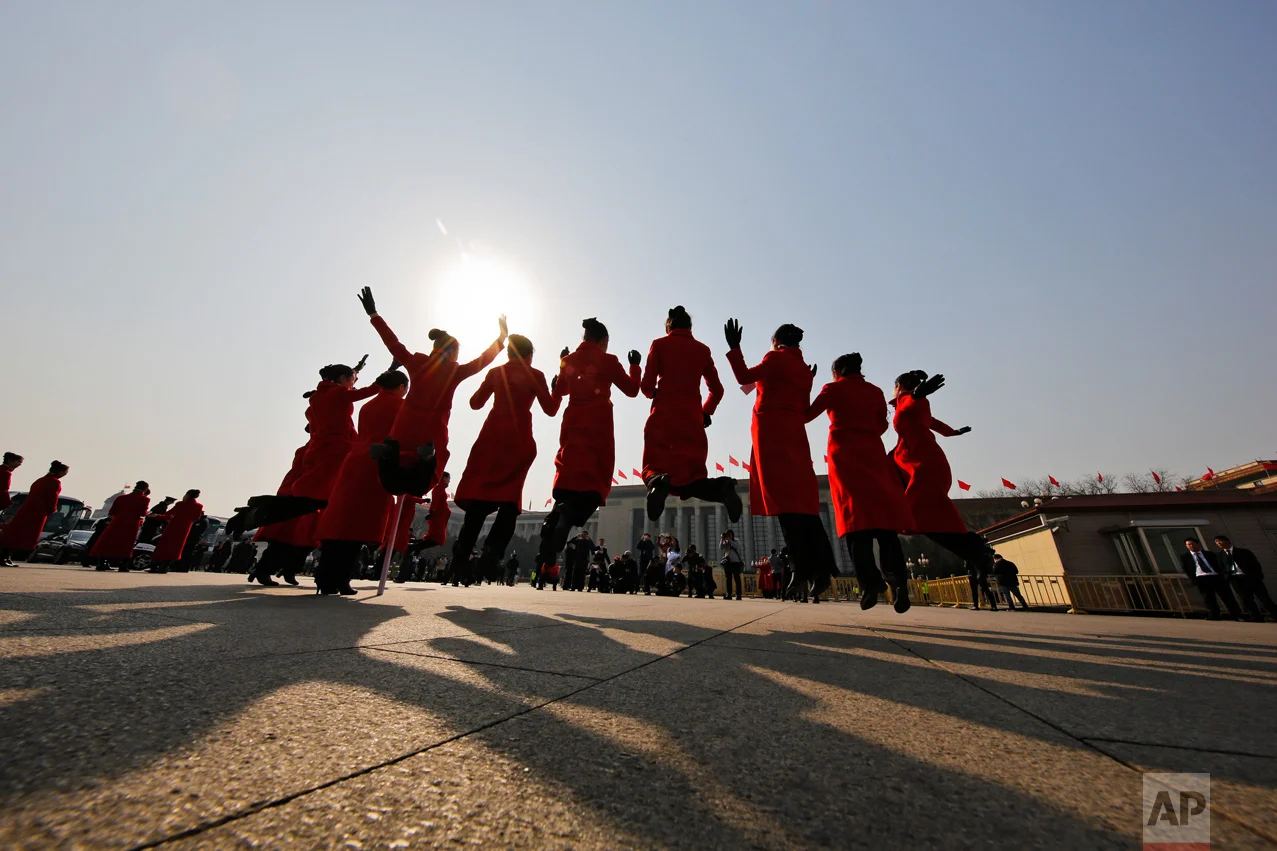 In this Friday, March 3, 2017 photo, hospitality staff jump as they pose for photographs on Tiananmen Square during the Chinese People's Political Consultative Conference (CPPCC) held at the Great Hall of the People in Beijing. (AP Photo/Andy Wong)
