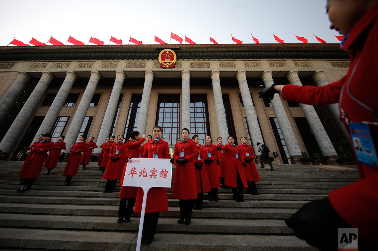 In this Friday, March 3, 2017 photo, a hospitality staffer directs her colleagues posing for photographs outside the Great Hall of the People during the Chinese People's Political Consultative Conference (CPPCC) in Beijing. (AP Photo/Andy Wong)