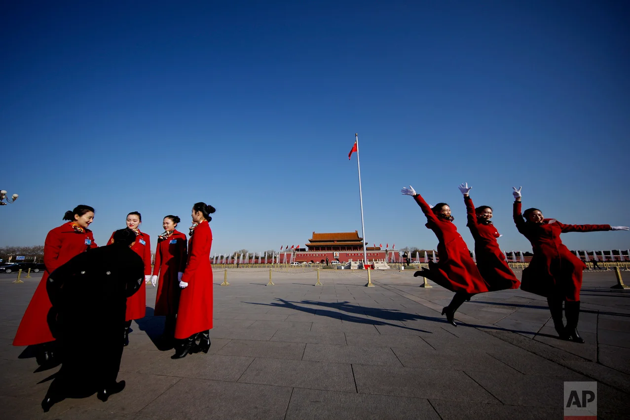 In this Sunday, March 5, 2017 photo, hospitality staff jump as they pose for photographs on Tiananmen Square during the National People's Congress held at the Great Hall of the People in Beijing. (AP Photo/Andy Wong)