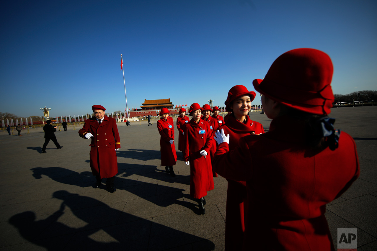In this Sunday, March 5, 2017 photo, a hospitality staffer poses her colleagues for photographs on Tiananmen Square during the National People's Congress held at the Great Hall of the People in Beijing. (AP Photo/Andy Wong)