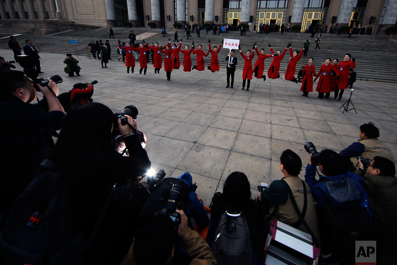 In this Friday, March 3, 2017 photo, hospitality staff jump as they pose for photographs in front of the Great Hall of the People during the Chinese People's Political Consultative Conference (CPPCC) in Beijing. (AP Photo/Andy Wong)