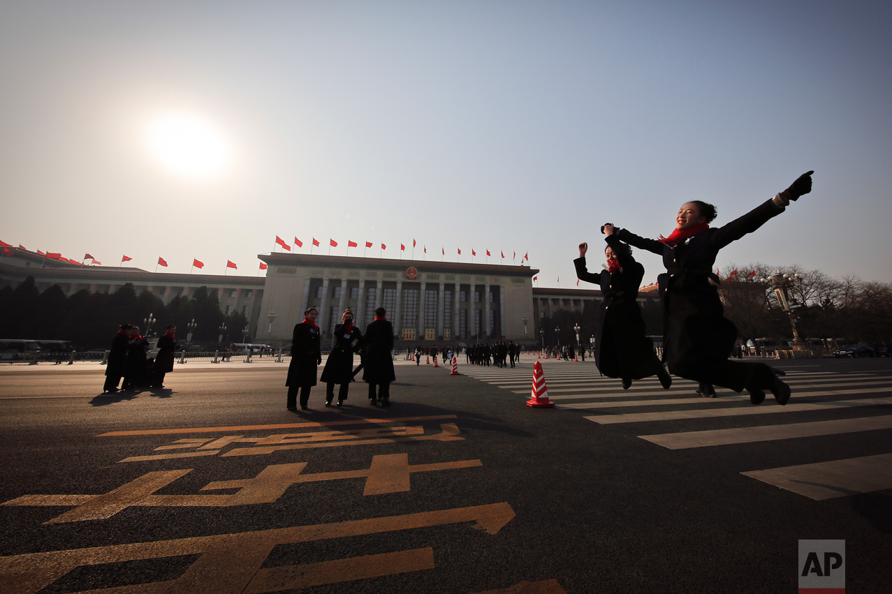 In this Friday, March 3, 2017 photo, hospitality staff jump as they pose for photographs on an empty street adjacent to the Great Hall of the People during the Chinese People's Political Consultative Conference (CPPCC) in Beijing. (AP Photo/Andy Wong)