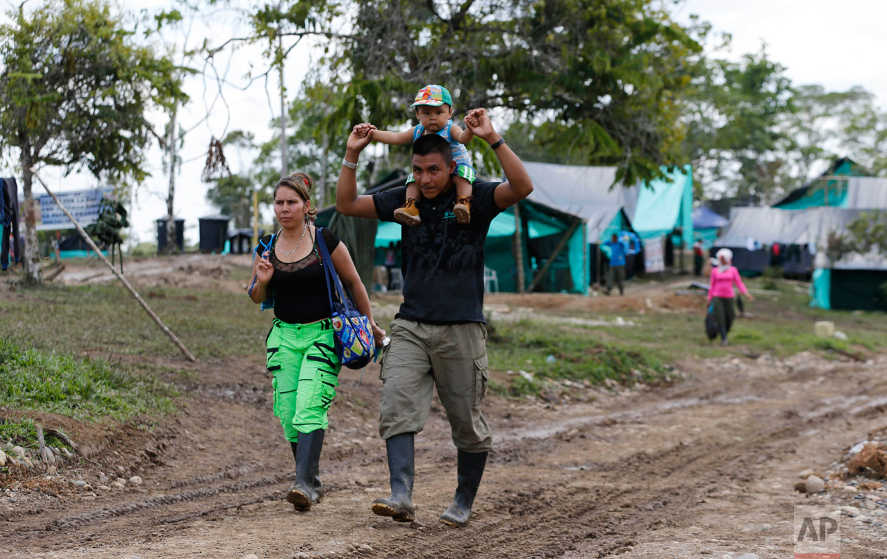 In this Tuesday, Feb. 28, 2017 photo, FARC rebel couple Jerly Suarez, left, and Vicente Pulecio walk to a cooking class with their 9-month-old son Dainer at a rebel camp in a demobilization zone in La Carmelita, in Colombia's southwestern Putumayo state. "It wasn't seen as viable for us to have children, because why is someone going to have them when there are bullets flying around?" said Suarez, referring to the loosening of rules on baring children after the rebel group and the government reached an agreement to end their armed conflict. (AP Photo/Fernando Vergara)