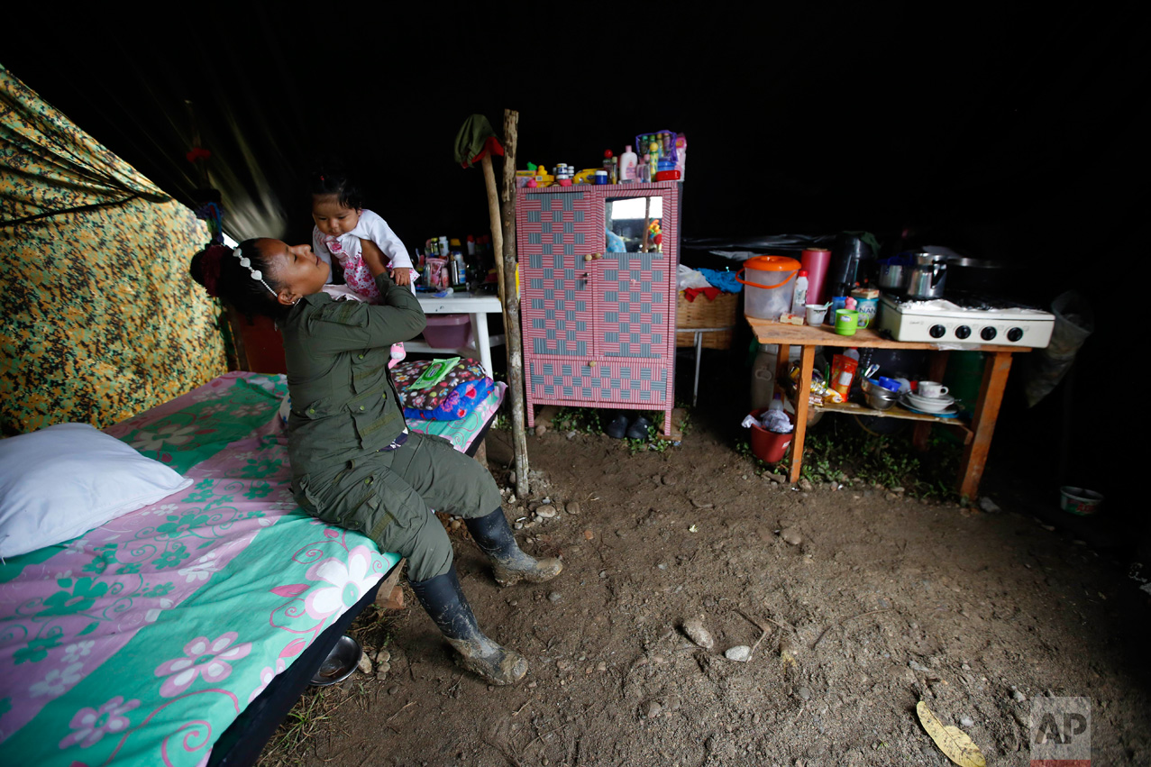 In this Tuesday, Feb. 28, 2017 photo, FARC rebel Sandra Saez plays with her 4-month-old daughter Manuela inside their tent at a rebel camp in a demobilization zone in La Carmelita, in Colombia's southwestern Putumayo state. The birth of babies at rebel camps and the arrival of older children who had been left with relatives during the conflict has injected a sense of optimism into camps where war-hardened rebels are beginning their transition to civilian life. (AP Photo/Fernando Vergara)