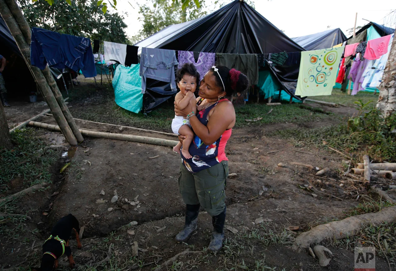 In this Tuesday, Feb. 28, 2017 photo, FARC rebel Sandra Saez holds her 4-month-old daughter Manuela outside her tent at a rebel camp in a demobilization zone in La Carmelita, in Colombia's southwestern Putumayo state. Maternity was always a hot topic of discussion within the rebel ranks, and the practice of forbidding female fighters from keeping their children at the camps flew in the face of the rebels’ claim that by enrolling female warriors they were freeing women from traditional gender roles that restricted women’s choices, and it angered many in this devoutly Roman Catholic country. (AP Photo/Fernando Vergara)