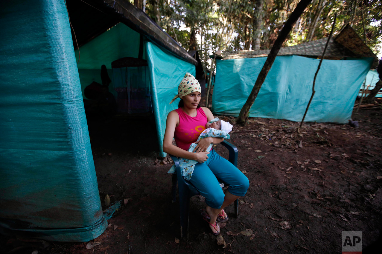 In this Tuesday, Feb. 28, 2017 photo, FARC rebel Marly Velasquez holds her 18-day-old-daughter Andry Talia during an interview outside her tent at a demobilization zone in La Carmelita in the Colombia's southwestern state of Putumayo. During times of war, constant confrontation with army soldiers and guard duties in jungle camps made raising children during the conflict difficult, if not impossible. Women were given steady supplies of contraceptives, and those who did get pregnant were presented with two options: leave the baby with the family members or end the pregnancy. (AP Photo/Fernando Vergara)