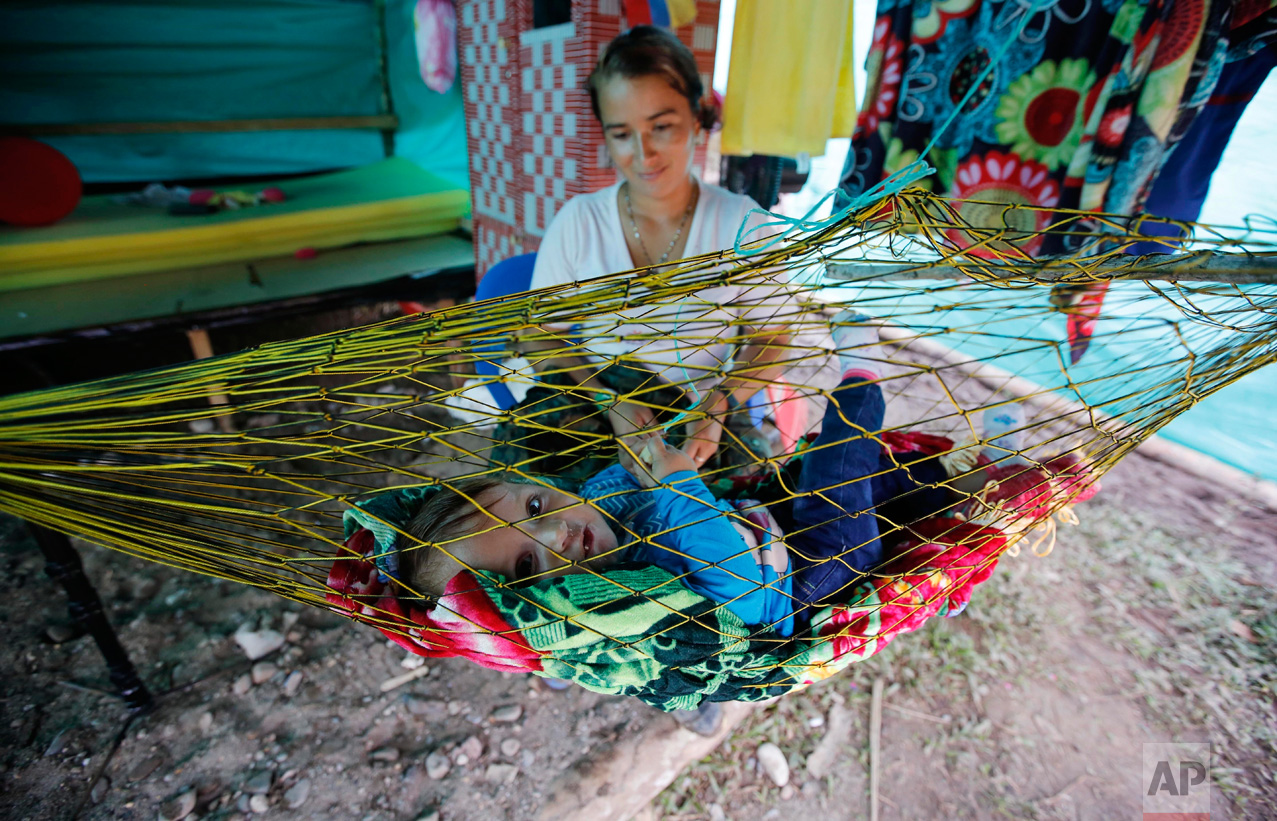 In this Tuesday, Feb. 28, 2017 photo, FARC rebel Nelcy Rios cares for her 9-month-old daughter Naiha Sofia inside her tent at a rebel camp in a demobilization zone in La Carmelita, in Colombia's southwestern Putumayo state. Some of the guerrilla mothers are giving birth in camps, but most at nearby hospitals. Many in Colombia are referring to the babies as the "children of peace." (AP Photo/Fernando Vergara)