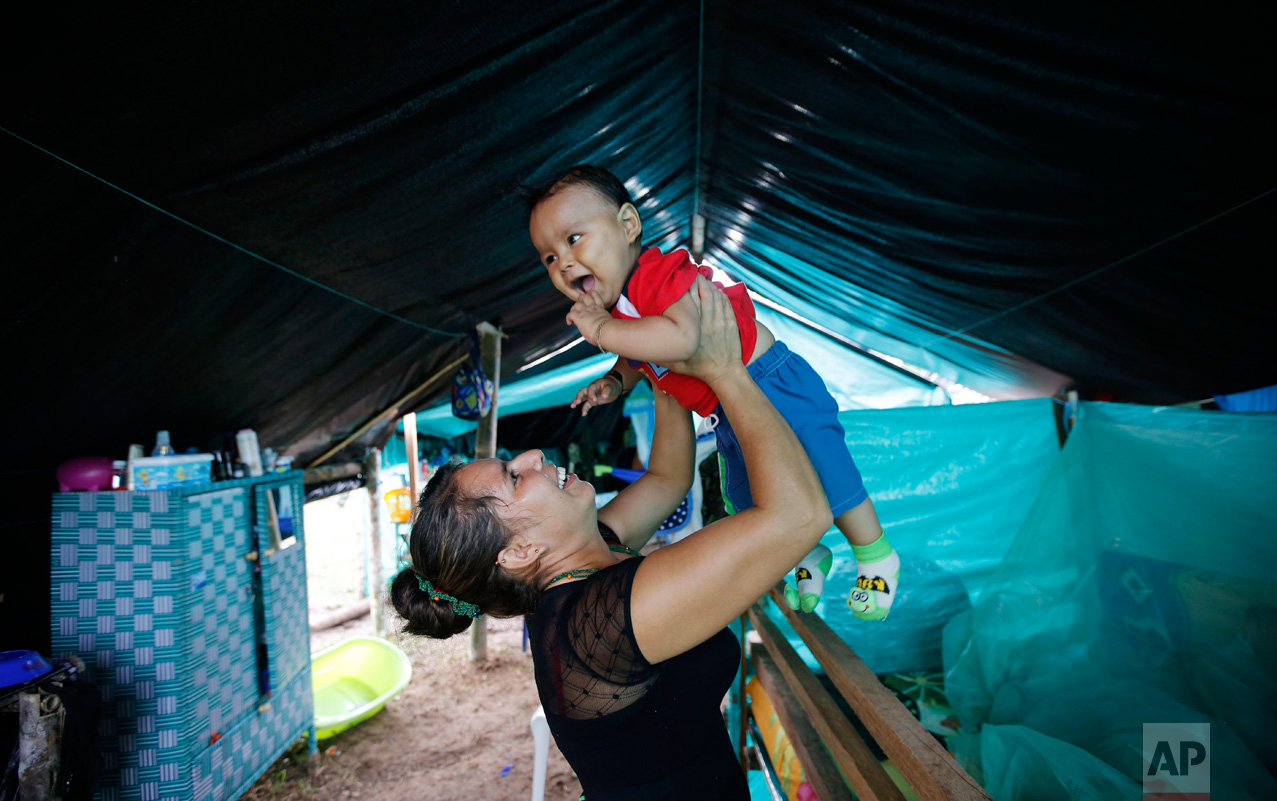 In this Tuesday, Feb. 28, 2017 photo, FARC rebel Jerly Suarez holds up her 9-month-old son Dainer inside her tent at a rebel camp in a demobilization zone in La Carmelita, in Colombia's southwestern Putumayo state. In La Carmelita, where 500 guerrillas are expected to turn over their weapons by June 1, women speak of both the arduous conditions in which they have begun their new lives as mothers and their hopes for raising children in a time of peace. (AP Photo/Fernando Vergara)