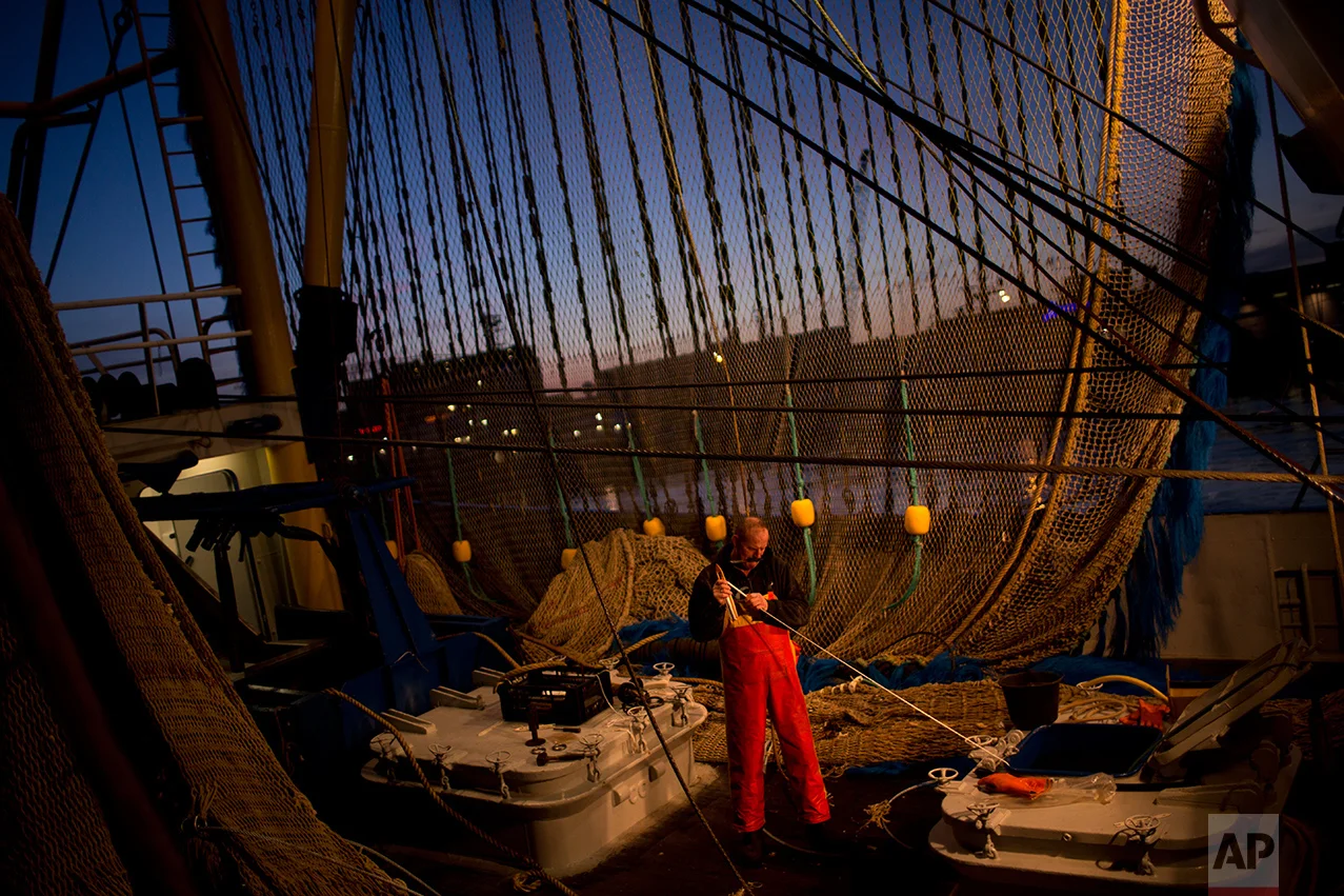 In this Friday, March 3, 2017 photo, a fisherman works on his ship fixing a fishing net at the port in The Hague, The Netherlands. (AP Photo/Emilio Morenatti)
