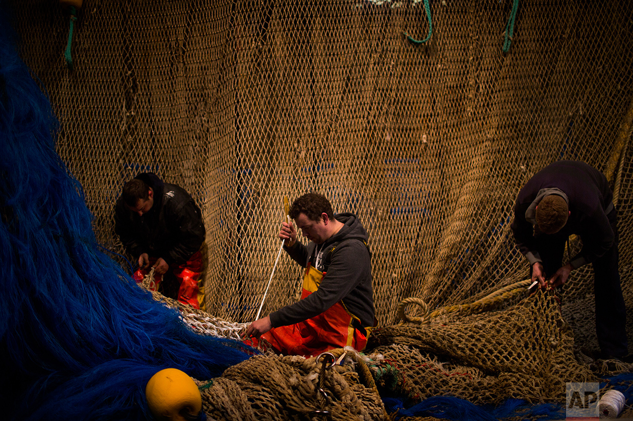 In this Friday, March 3, 2017 photo, fishermen of the Maarten-Jacob ship work fixing their fishing net at the port in The Hague, The Netherlands. (AP Photo/Emilio Morenatti)