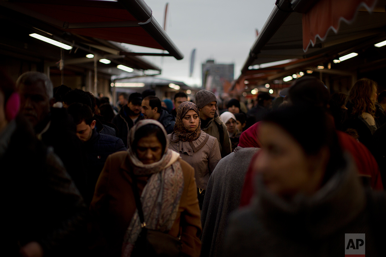 In this Saturday, March 4, 2017 photo, people walk along street stalls at a fruit market in The Hague, The Netherlands. In The Hague's most culturally diverse neighbourhoods, many women wear Muslim headscarves. In the market, young Muslim women eating battered fried fish, a Dutch favourite, took dainty, careful bites to avoid splashing grease on their hijabs. (AP Photo/Emilio Morenatti)