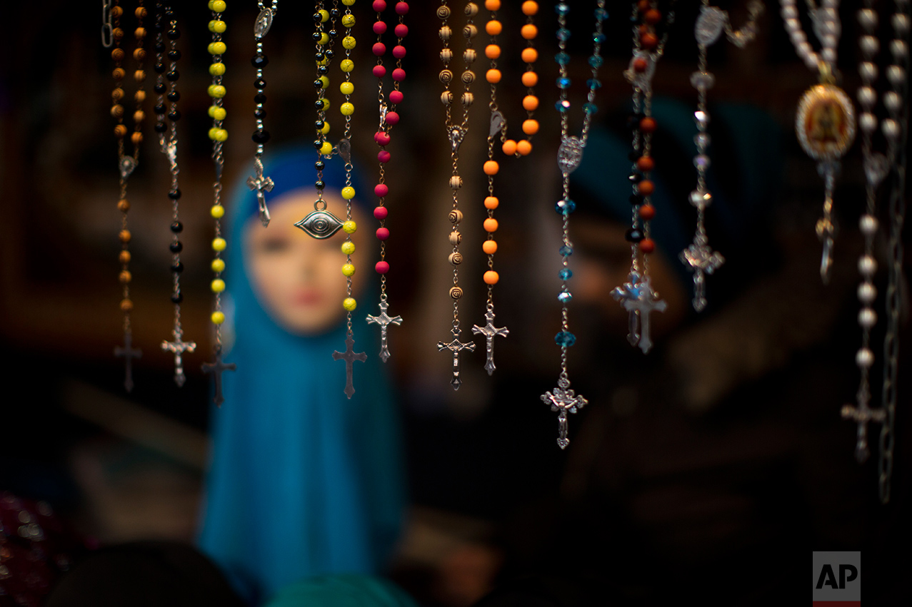 In this Saturday, March 4, 2017 photo, rosary beads are displayed for selling next to a mannequin wearing a headscarf in a market stall at The Hague, The Netherlands. In The Hague's most culturally diverse neighbourhoods, many women wear Muslim headscarves. (AP Photo/Emilio Morenatti)